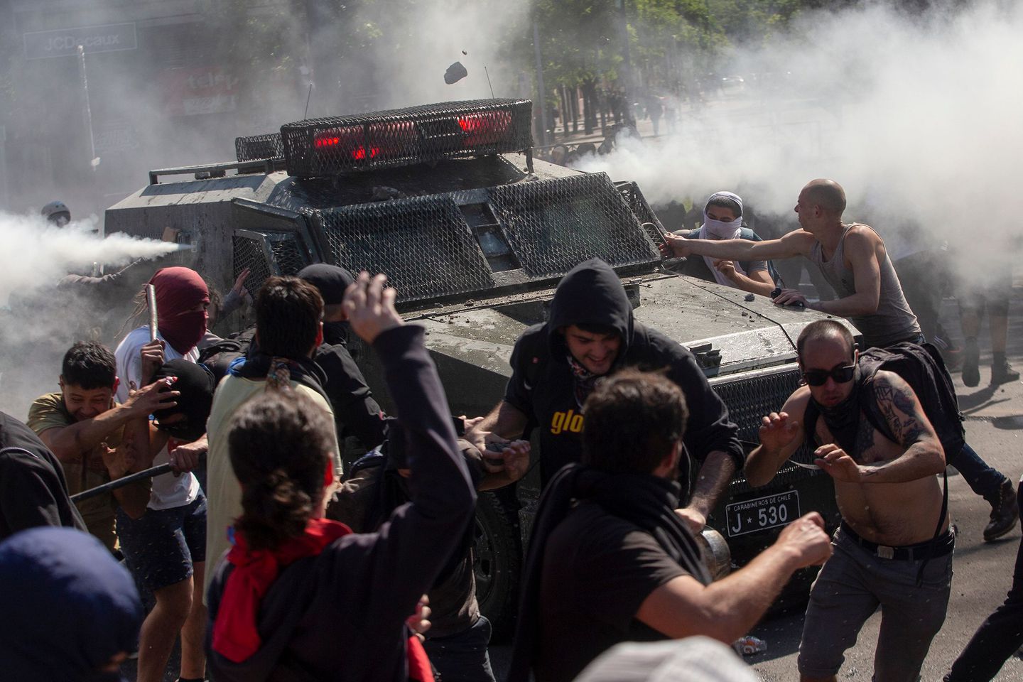 Manifestantes se enfrentan a un vehículo policial en Santiago (Foto: Claudio Reyes/ AFP)