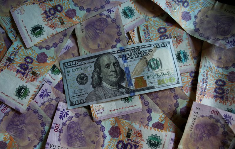 Billetes de cien pesos argentinos se encuentran debajo de un billete de cien dólares de Estados Unidos. Foto de archivo 3 Sep 2019. REUTERS/Agustin Marcarian/Illustration