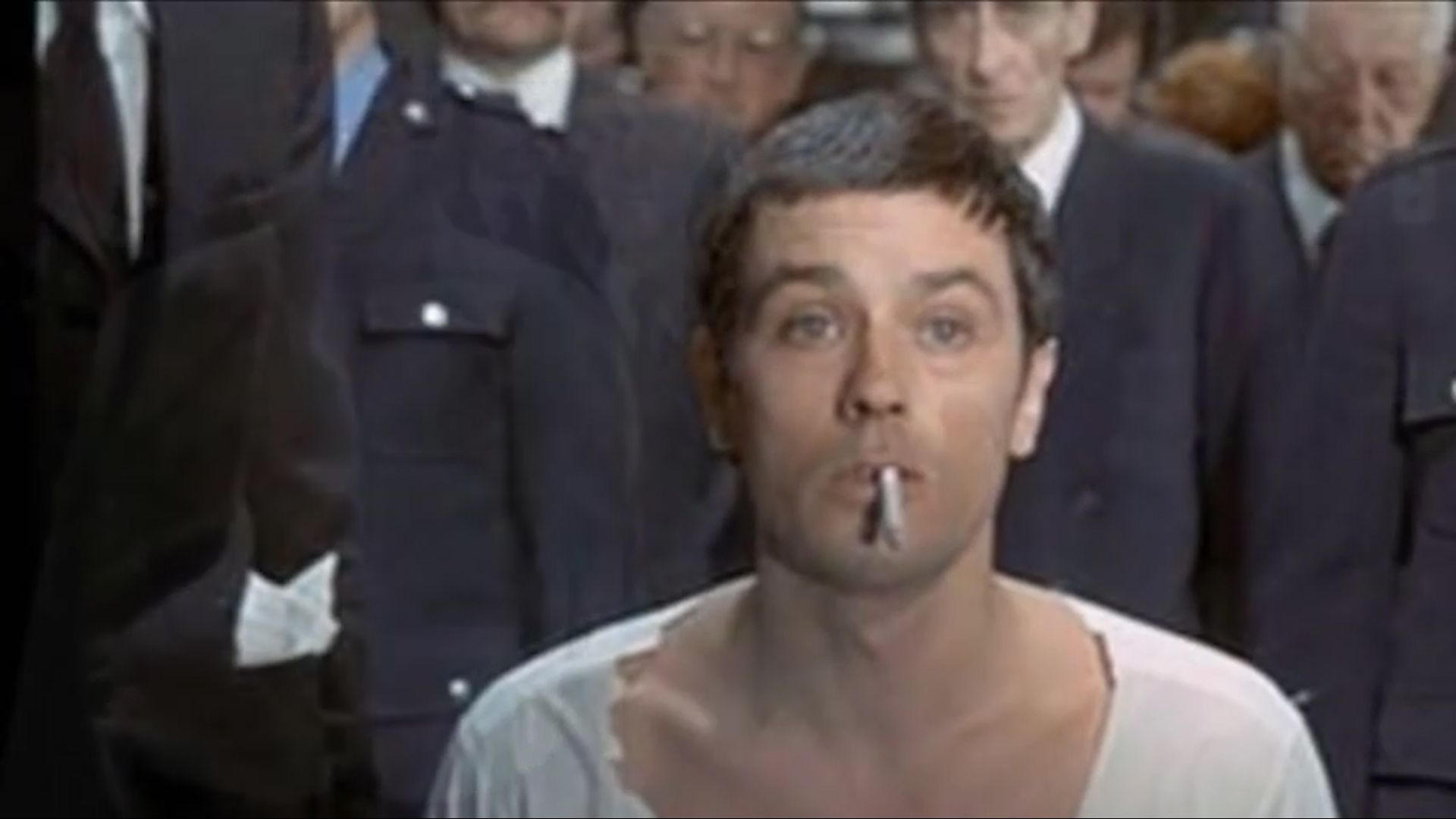 Alain Delon fuma su último cigarrillo antes de la ejecución, en el film Dos contra la ciudad (1973). El cuello de la camisa del reo era recortado para dejar la nuca descubierta