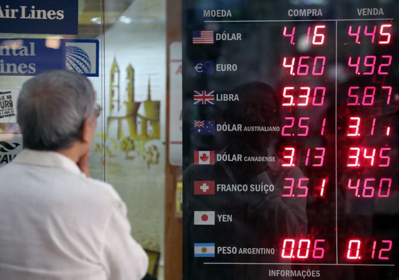 Foto de Archivo: Un hombre observa un tablero que muestra el tipo de cambio del real brasileño y el dólar de Estados Unidos, y varias otras monedas extranjeras en Río de Janeiro, Brasil 26 de noviembre de 2019. REUTERS/Sergio Moraes