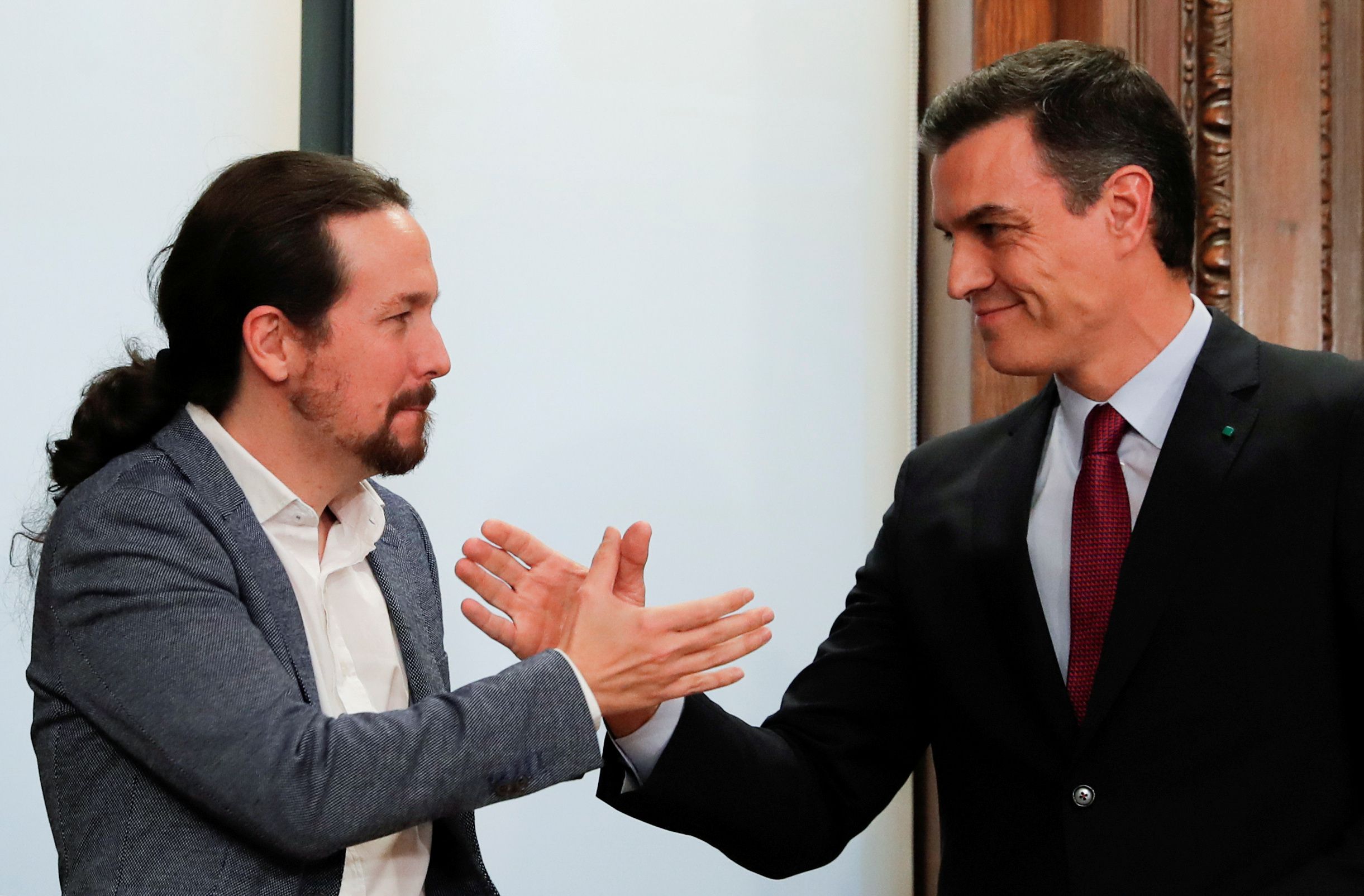 Sánchez y Pablo Iglesias se dan la mano al presentar su acuerdo de coalición en el Parlamento español, el 30 de diciembre de 2019 (REUTERS/Susana Vera/Archivo Foto)