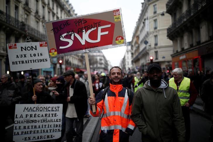 Un trabajador del operador de servicios de trenes SNCF muestra un cartel durante una marcha en París como parte de la huelga de 36 días contra la reforma al sistema de pensiones de Francia. REUTERS/Benoit Tessier