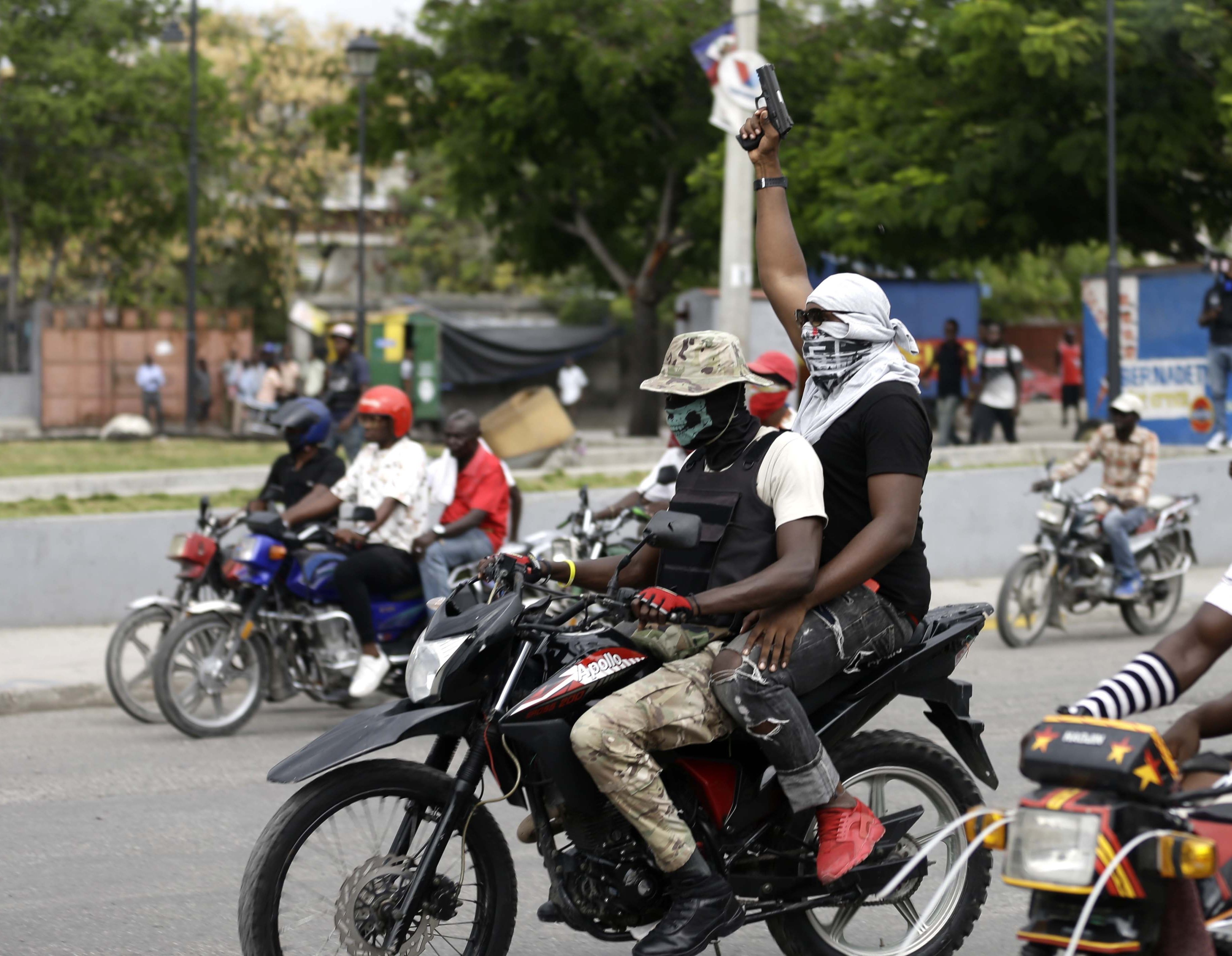Policías fuera de servicio en motocicletas disparan sus armas al aire durante una protesta para exigir mejores salarios y condiciones laborales en Puerto Príncipe, Haití, el domingo 23 de febrero de 2020. (AP Foto/Dieu Nalio Chery)