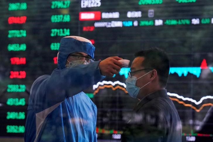 Un trabajador con traje de protección toma la temperatura corporal de una persona en el edificio del Shanghai Stock Exchange, en China. 