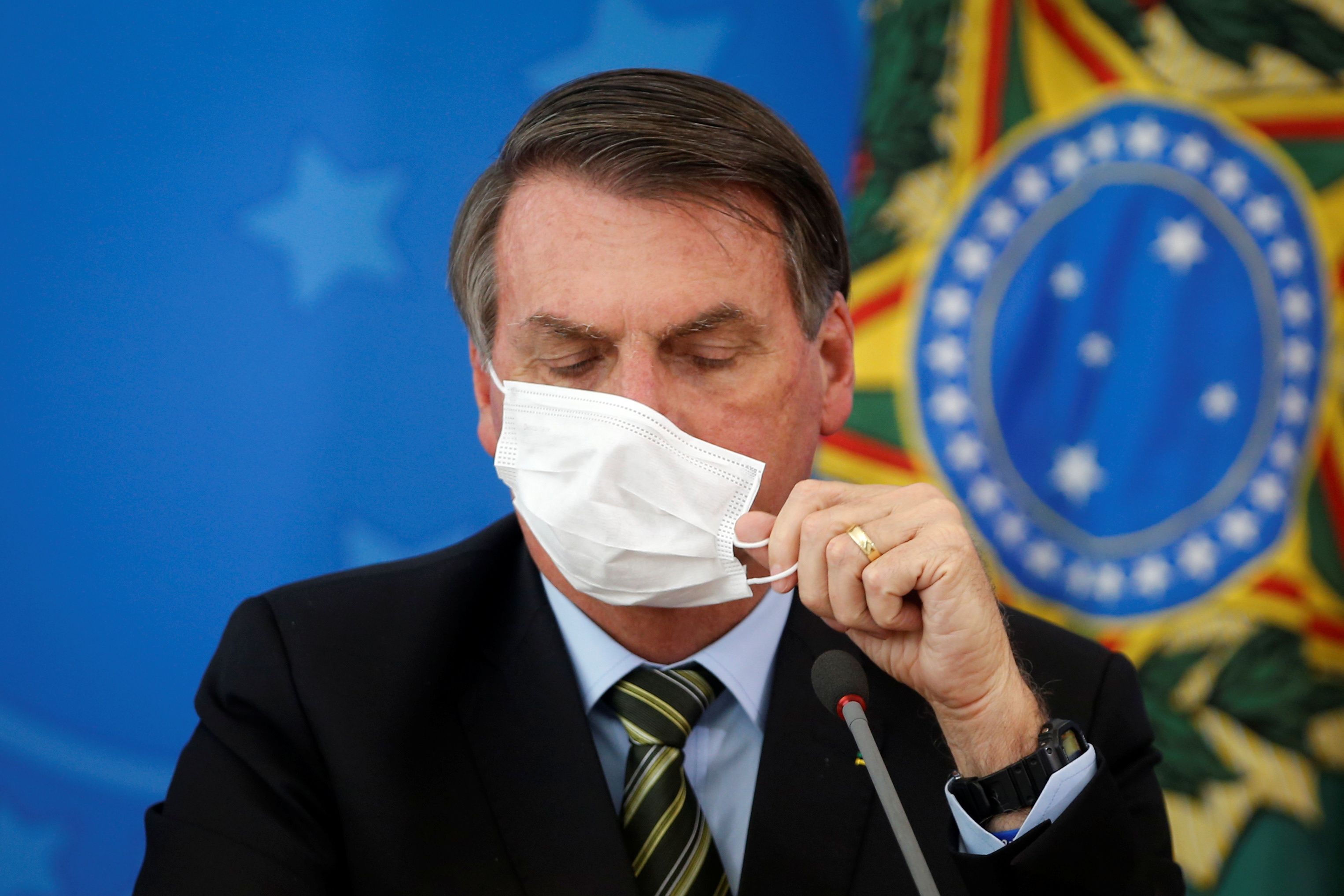 El presidente de Brasil, Jair Bolsonaro, se ajusta su mascarilla durante una locución pública. Foto: REUTERS/Adriano Machado