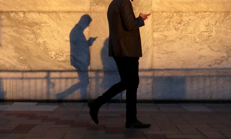 FILE PHOTO: An unidentified man using a smart phone walks through London's Canary Wharf financial district in the evening light in London, Britain, September 28, 2018. REUTERS/Russell Boyce/File Photo