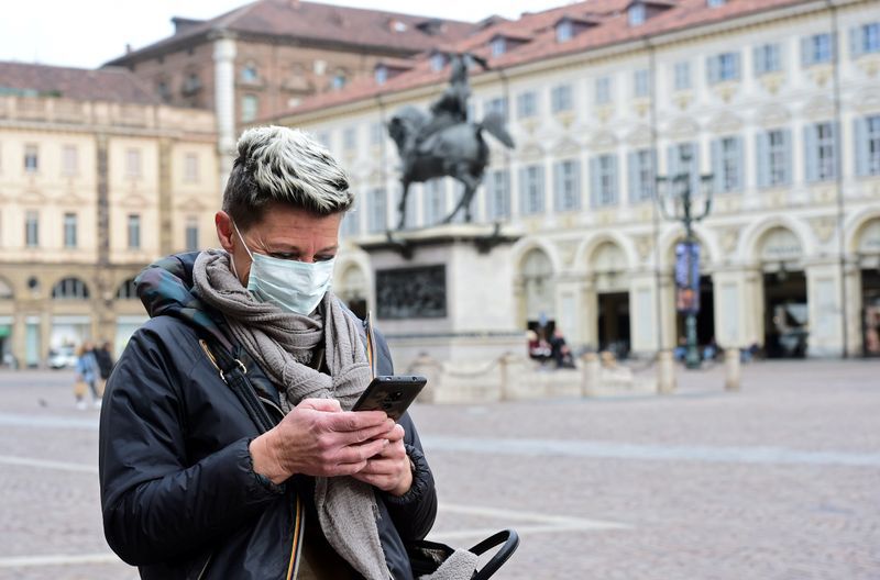 Una mujer que lleva una máscara protectora usa su teléfono móvil, mientras un brote de coronavirus continúa creciendo en el norte de Italia, en Turín (Italia), el 27 de febrero de 2020. REUTERS/Massimo Pinca
