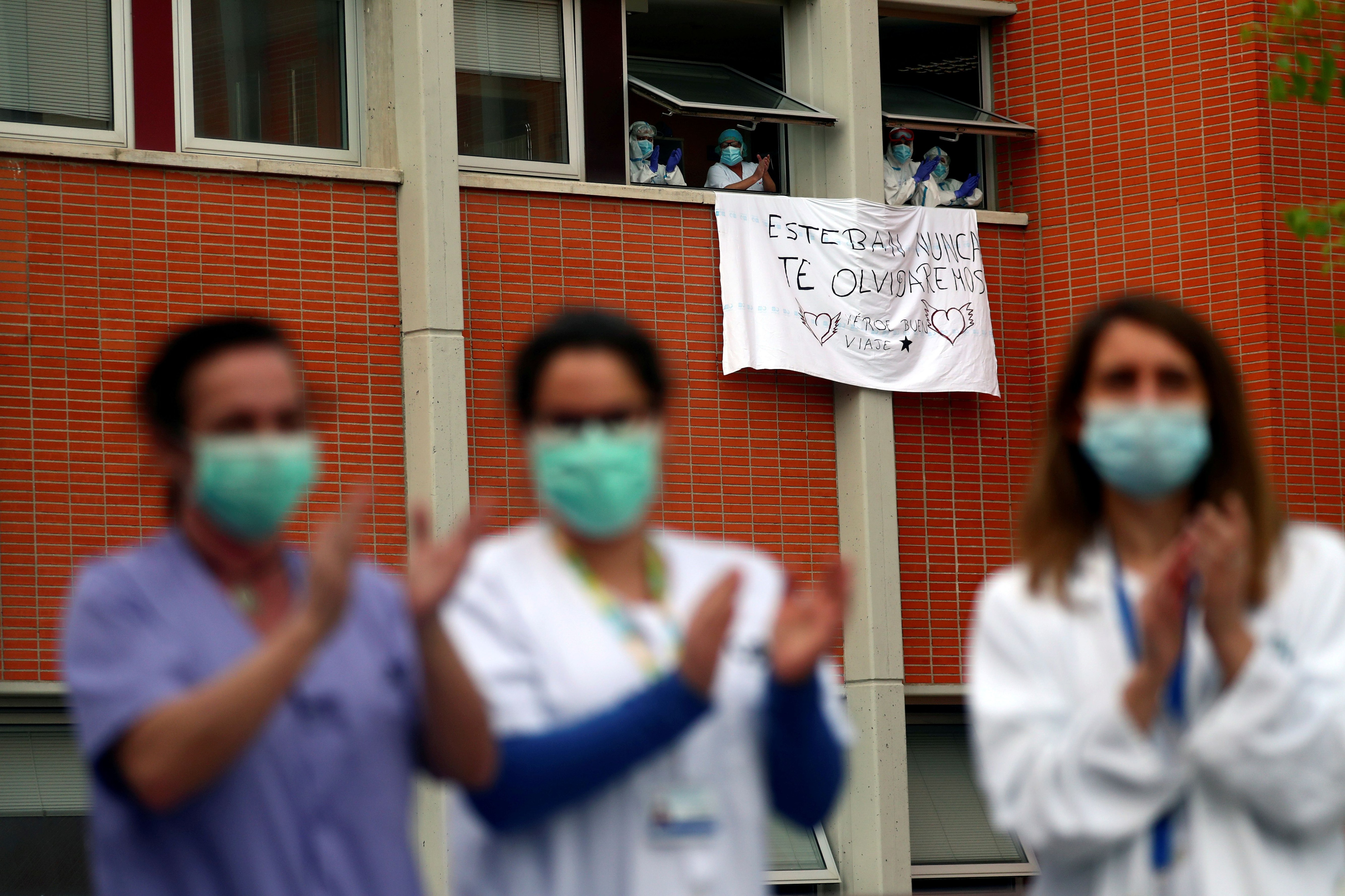 Trabajadores aplauden junto a una bandera por Esteban, un enfermero que murió por coronavirus (Reuters)