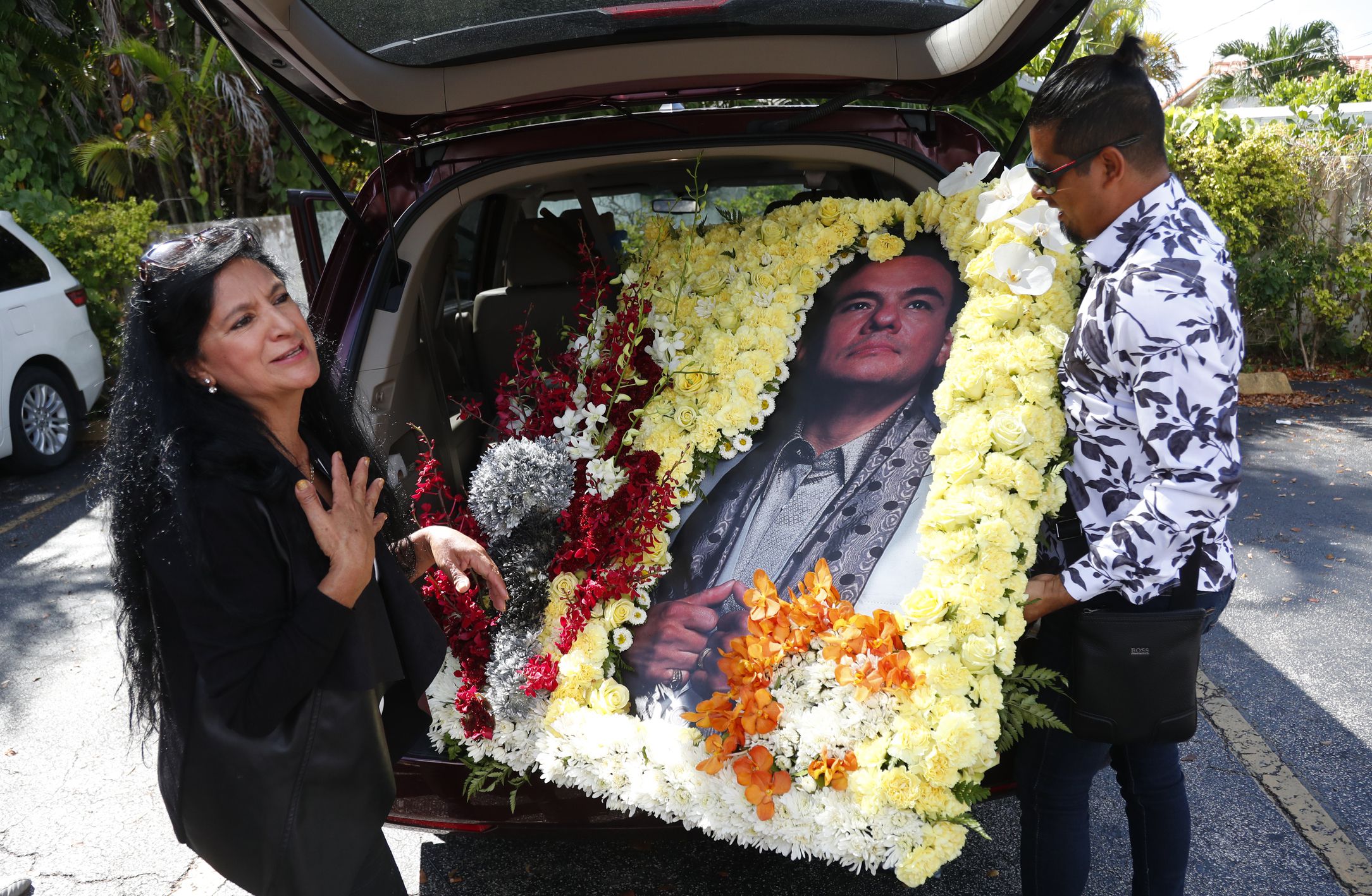 Angela Paise, left, and Luis Brito, who is known as "El Mago de las flores,"or "The flower magician," show off a flower arrangement they made and brought to the wake of the late Mexican singer Jose Jose, Friday, Oct. 4, 2019, in Miami. The singer, beloved for his melancholy ballads, died last Saturday in Miami at age 71. (AP Photo/Wilfredo Lee)