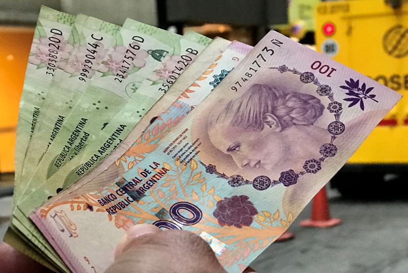 Foto de archivo de un hombre sosteniendo varios billetes de pesos argentinos fuera de un banco en el distrito financiero de Buenos Aires. Ago 30, 2018. REUTERS/Marcos Brindicci
