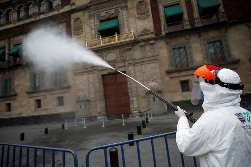 Trabajadores rocían desinfectante frente al Palacio Nacional después de ser decretada la Fase 3 de la pandemia en México (Foto: Reuters/Gustavo Graf)