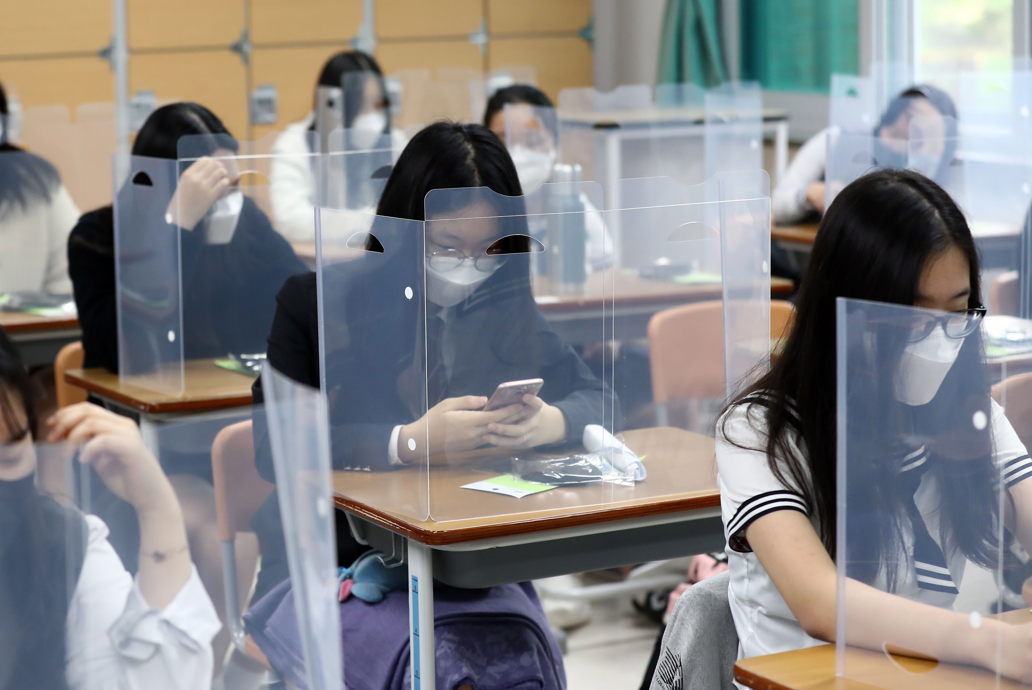Los estudiantes esperan que la clase comience con paneles de plástico colocados en sus escritorios en la Escuela Secundaria Jeonmin en Daejeon, Corea del Sur. (EFE/EPA/YONHAP) 