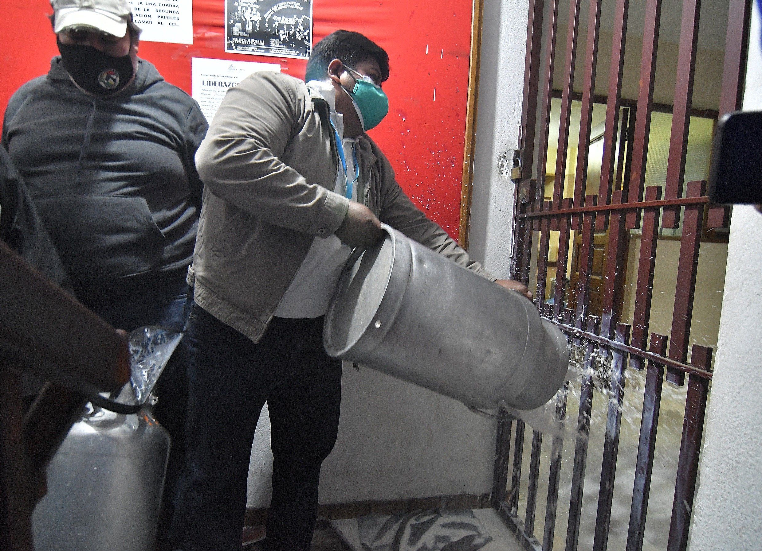 Lecheros bolivianos derraman leche este lunes en la sede de la gobernación regional de Cochabamba (Bolivia). EFE/Jorge Ábrego 