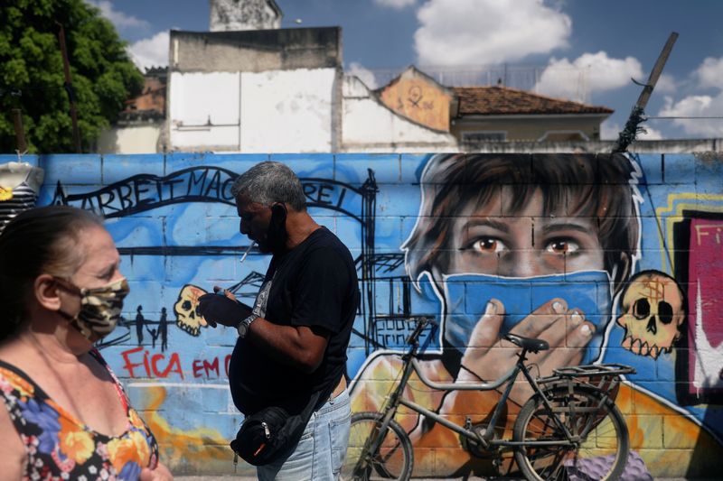 IMAGEN DE ARCHIVO. Personas utilizando mascarillas pasan frente a un grafiti en medio de la pandemia de coronavirus, en Río de Janeiro, Brasil, Septiembre 2, 2020. REUTERS/Pilar Olivares/