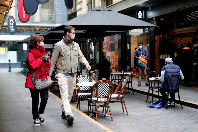 FILE PHOTO: People walk past a cafe after the coronavirus disease (COVID-19) restrictions were eased for the state of Victoria, in Melbourne, Australia, October 28, 2020. REUTERS/Sandra Sanders