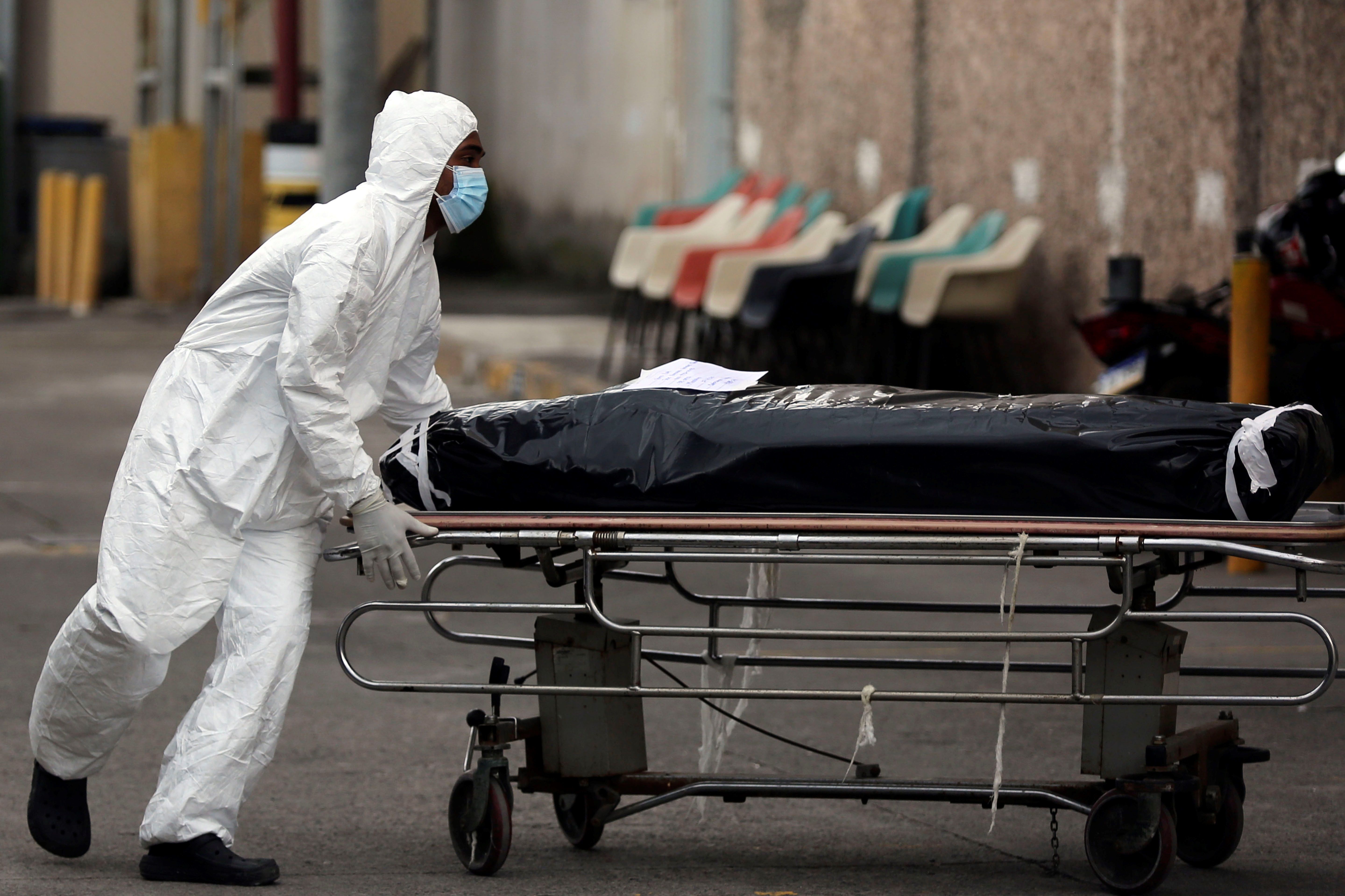 Un enfermero vestido con traje de bioseguridad traslada el cuerpo de una persona que murió por coronavirus en Tegucigalpa (Honduras). EFE/Gustavo Amador/Archivo 
