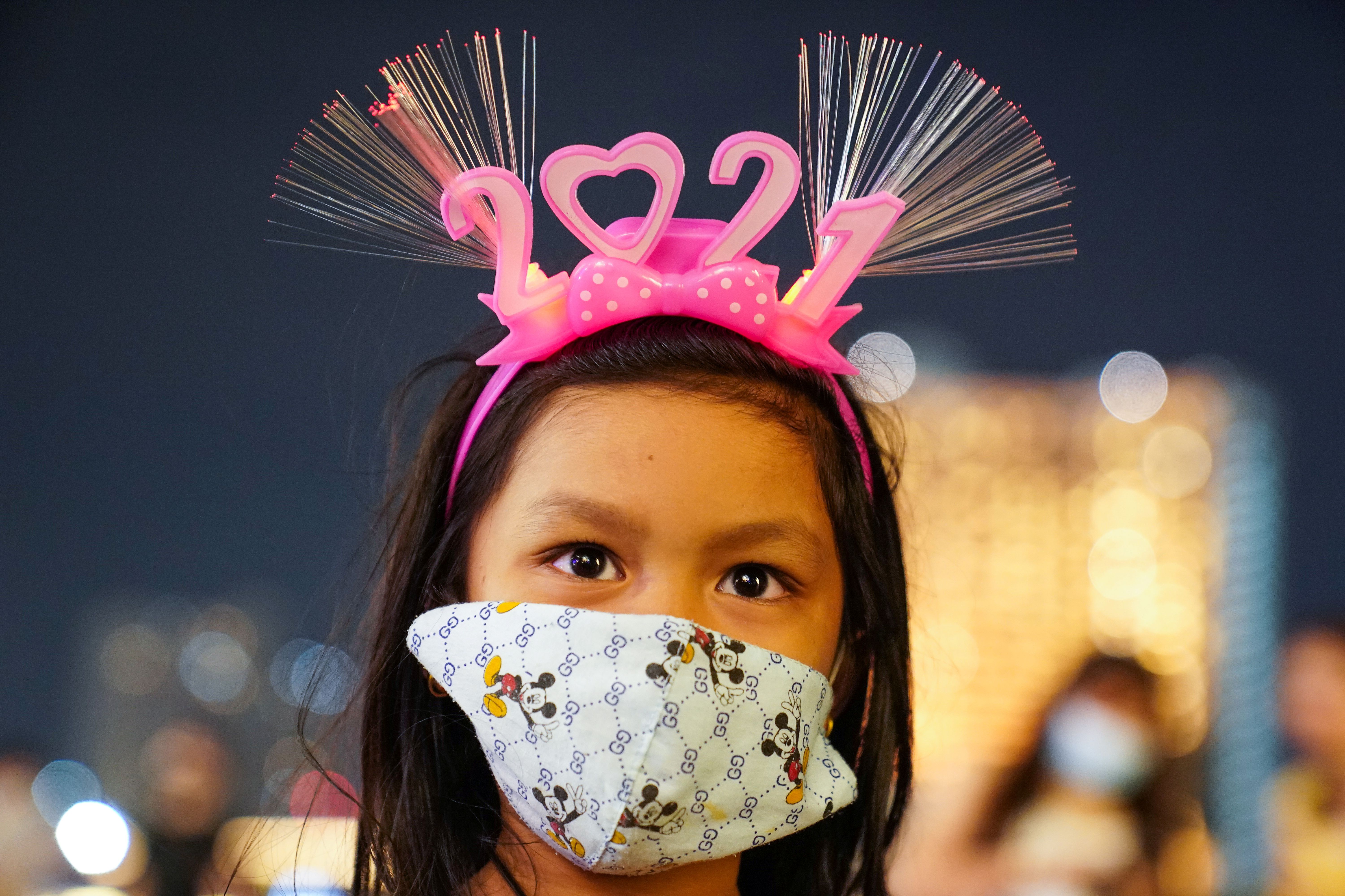Una niña con mascarilla espera la llegada del 2021 en Bangkok, Tailandia. REUTERS/Athit Perawongmetha