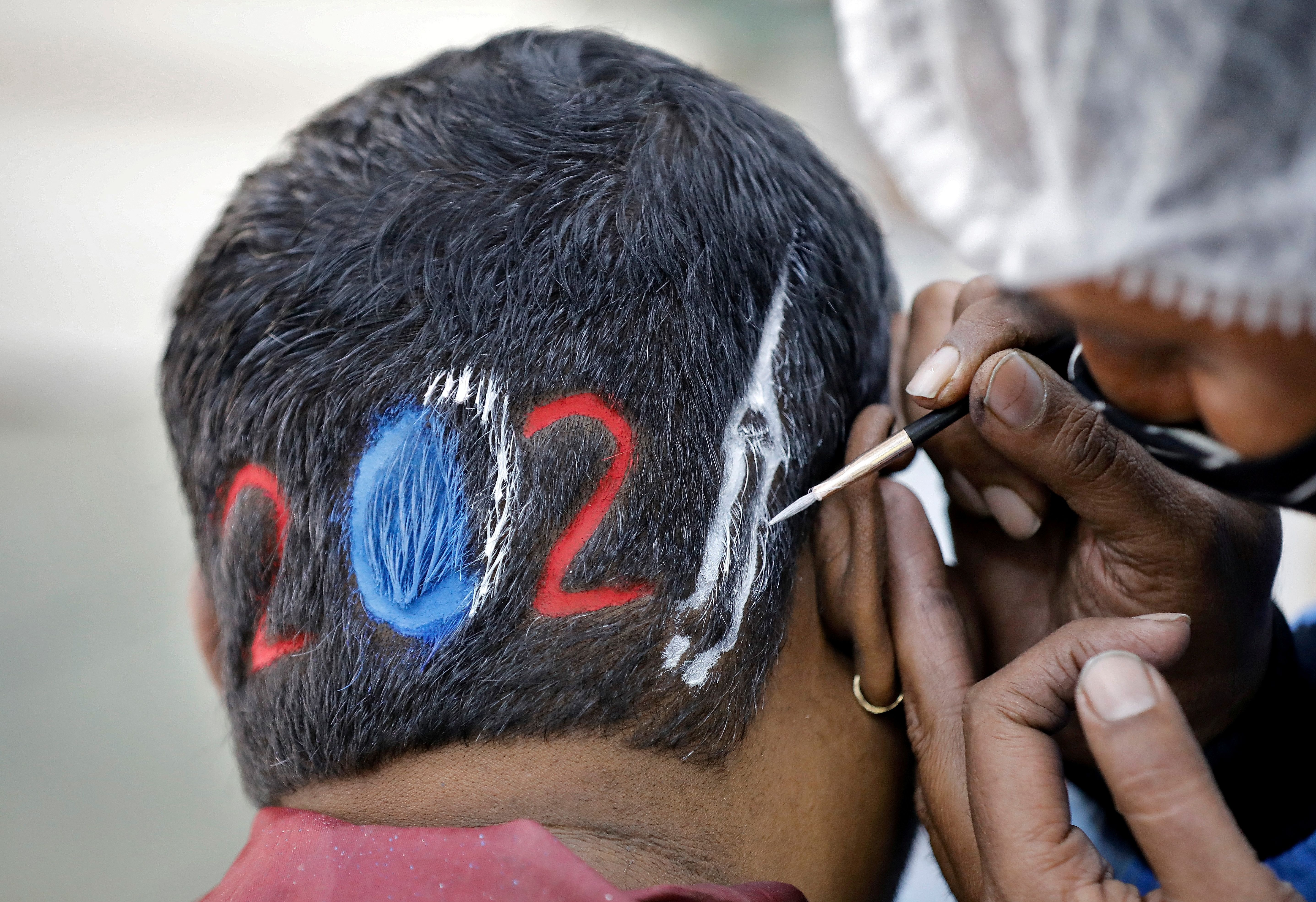 Un peluquero diseña un corte para un cliente que espera con ansias la llegada del 2021 en Ahmedabad, India. REUTERS/Amit Dave