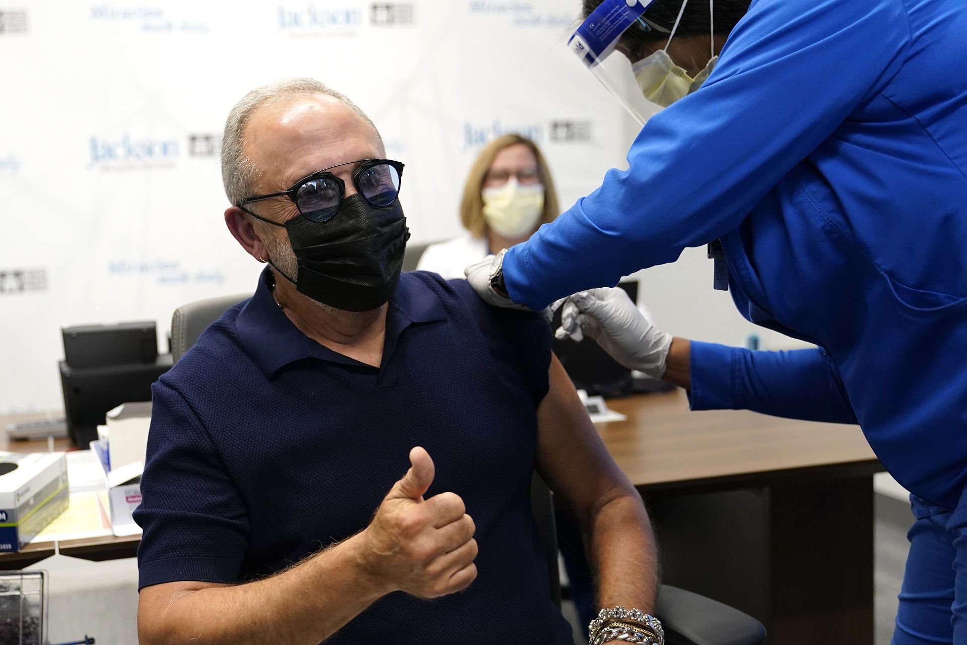 Music producer Emilio Estefan, 67, gives the thumbs-up while he receives the Pfizer-BioNTech COVID-19 vaccine at Jackson Memorial Hospital, Wednesday, Dec. 30, 2020, in Miami. Jackson Health System is starting to vaccinate people over the age of 65 this week. (AP Photo/Lynne Sladky)