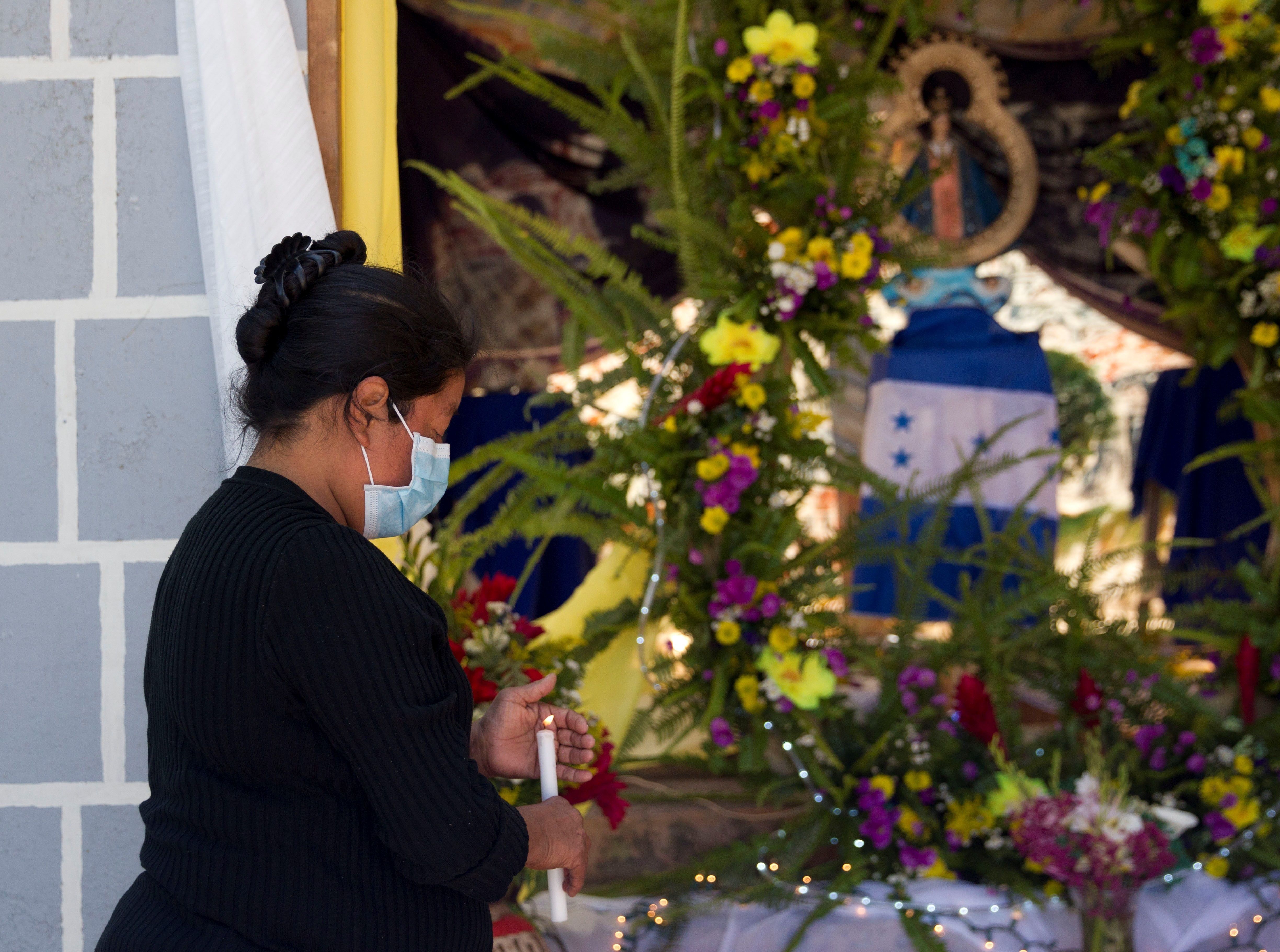 Una mujer enciende una vela frente a un altar improvisado con una replica de la Virgen de Suyapa hoy en Tegucigalpa (Honduras). EFE/Gustavo Amador 