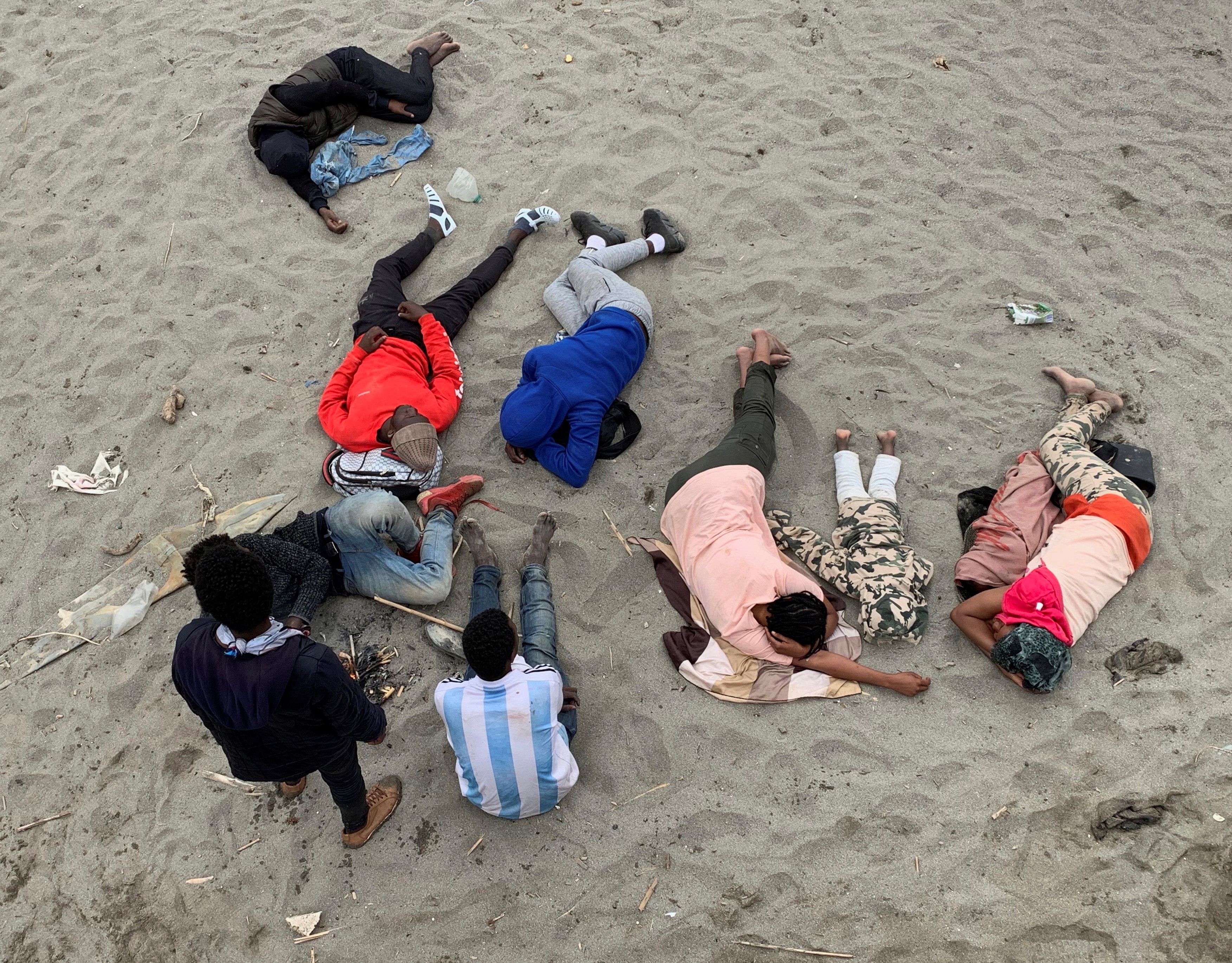 Un grupo de personas descansa en la playa de la localidad de Fnideq (Castillejos) antes de cruzar los espigones de Ceuta este martes en una avalancha de inmigrantes sin precedentes en España al registrarse la entrada en 24 horas de 5.000 personas (un tercio de ellas menores). EFE/ Mohamed Siali 