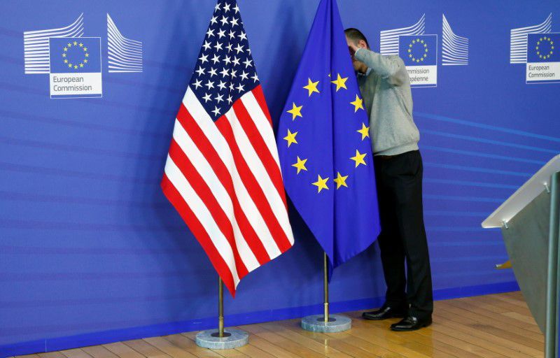 FOTO DE ARCHIVO: Un hombe ajusta una bandera de la Unión Europea junto a otra de Estados Unidos en la sede de la Comisión Europea en Bruselas, Bélgica, el 11 de noviembre de 2013. REUTERS/François Lenoir