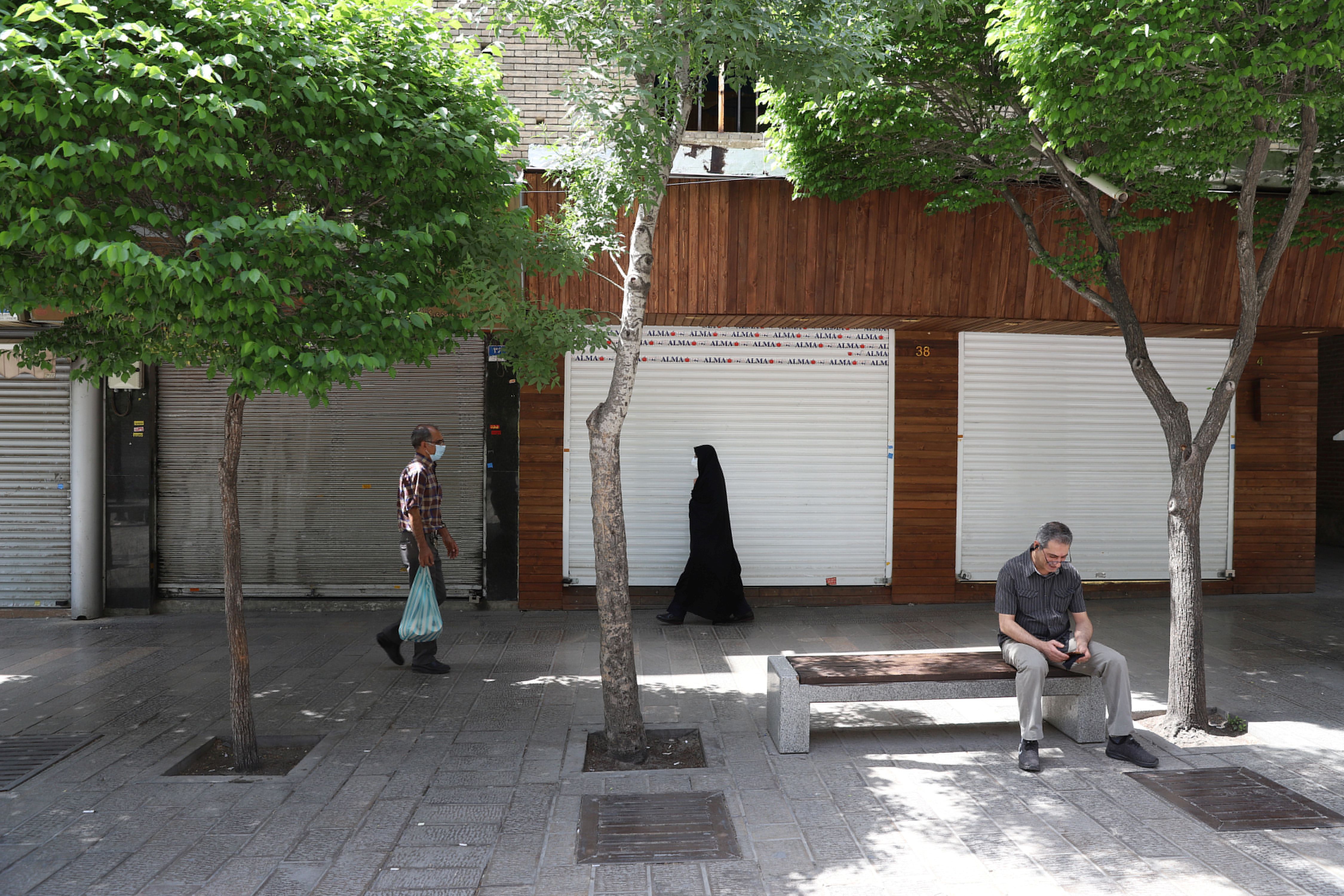 La gente camina frente a las tiendas cerradas tras el endurecimiento de las restricciones para frenar el aumento de los casos de COVID-19, en Teherán, Irán. Majid Asgaripour / WANA (Agencia de Noticias de Asia Occidental) a través de REUTERS