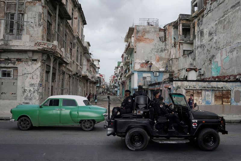 Un vehículo de las fuerzas especiales de la dictadura pasa junto a un carro de la época en la que se instauró el régimen en el centro de La Habana