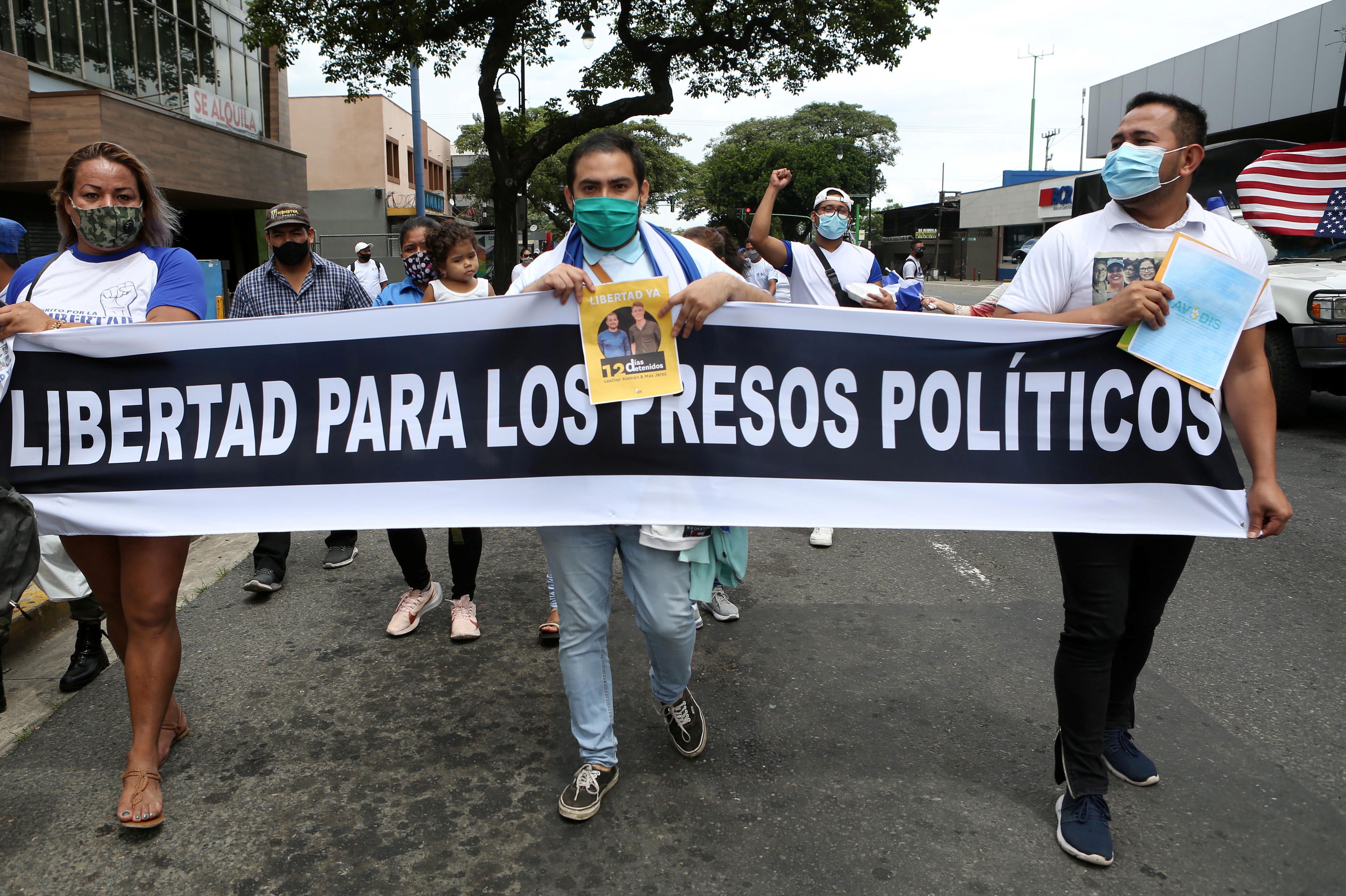 Nicaragüenses exiliados en Costa Rica sostienen una pancarta en la que se lee "Libertad para los presos políticos" durante una marcha denominada "Nicaragua no estás sola" (Reuters)