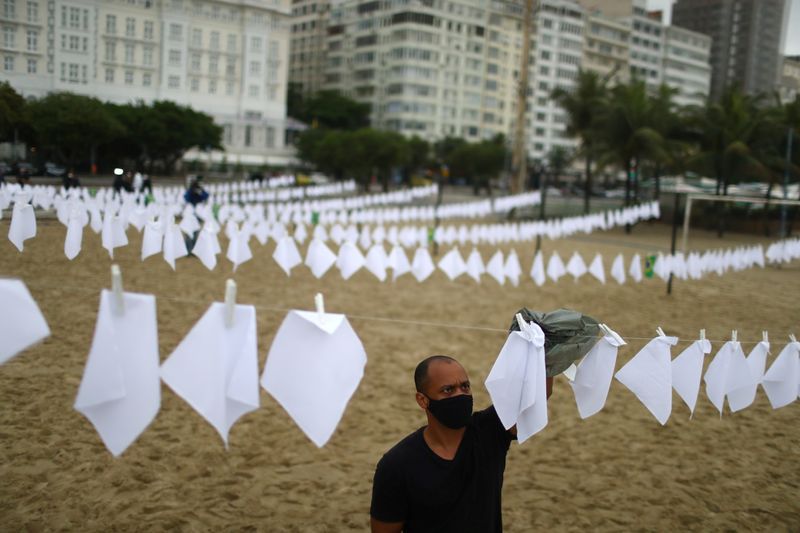 Un miembro de la ONG Río de Paz coloca pañuelos blancos para rendir homenaje a las 600.000 personas que han muerto por el COVID-19 en el país, en la playa de Copacabana, Río de Janeiro (Foto: REUTERS/Pilar Olivares)