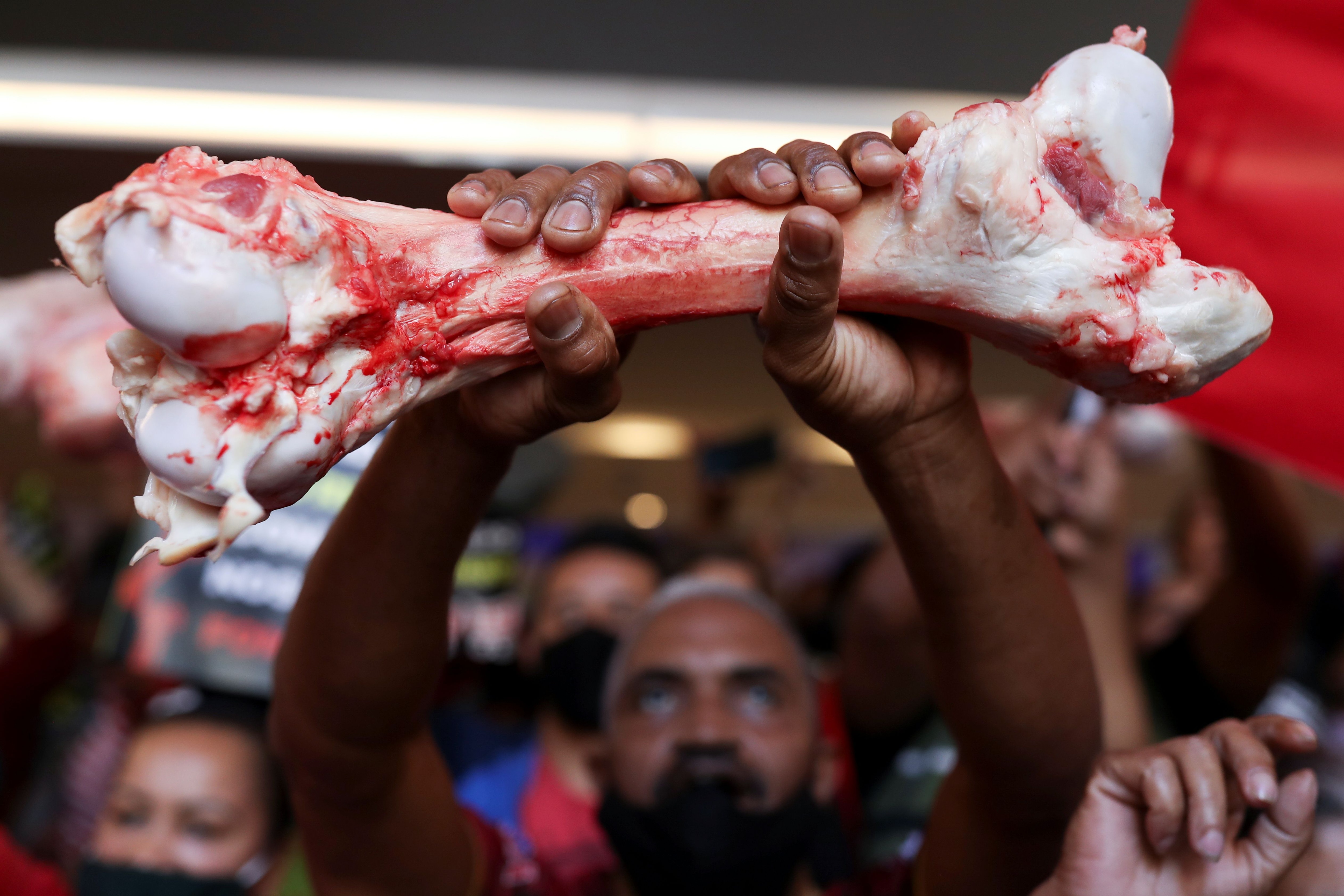 Un hombre sostiene un hueso mientras los manifestantes del Movimiento de Trabajadores sin Techo (MTST) protestan en la Bolsa de Valores B3 de Brasil contra la inflación y el precio de los alimentos y otros artículos esenciales en el centro de Sao Paulo, Brasil, 23 de septiembre de 2021. (REUTERS/Amanda Perobelli)