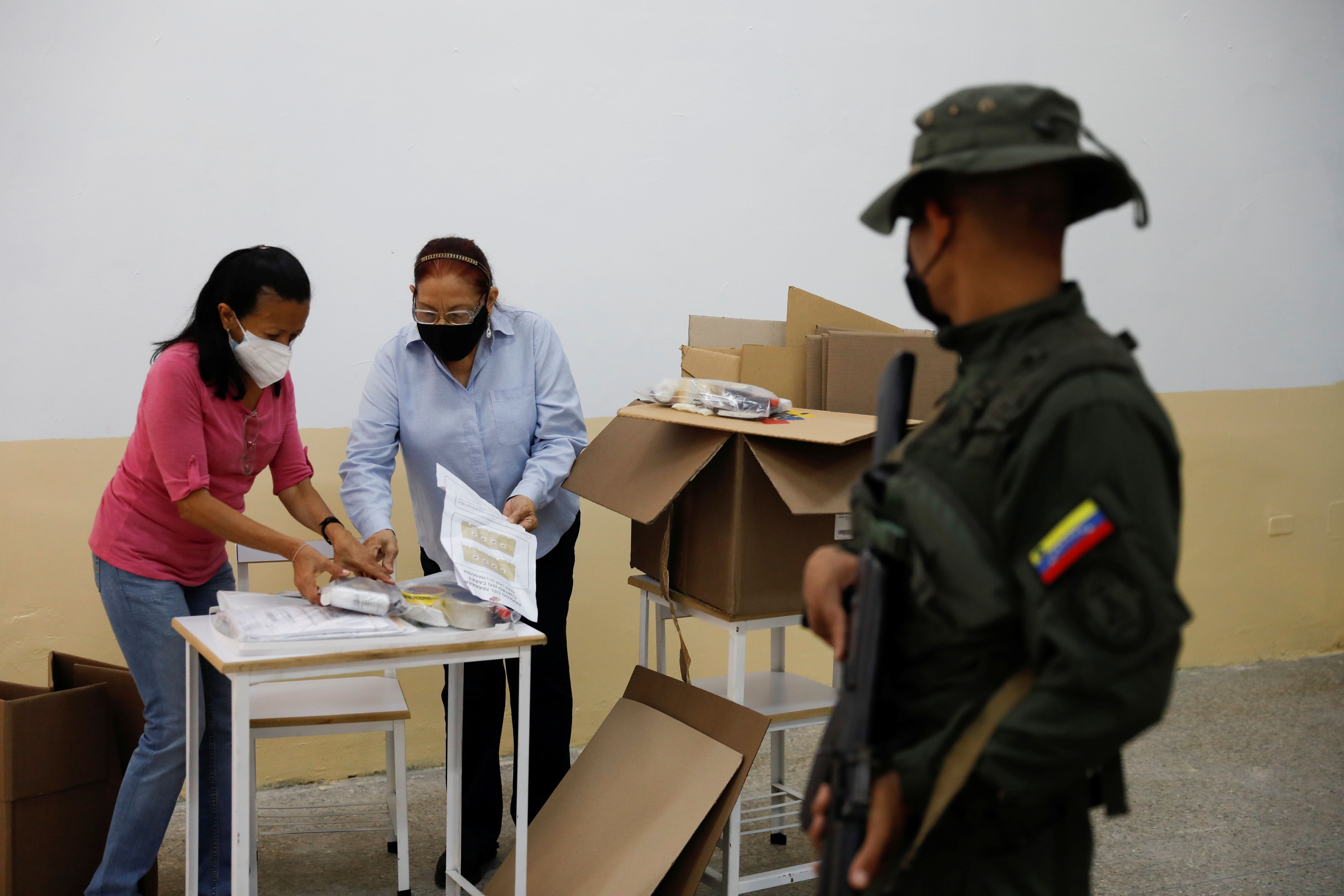 Trabajadores electorales revisando el material electoral son escoltados por un miembro de la Guardia Nacional Bolivariana, durante los preparativos para las elecciones regionales y locales del domingo, en Caracas, Venezuela, 19 de noviembre de 2021. REUTERS/Leonardo Fernández Viloria