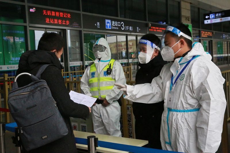Policías y miembros del personal con equipo de protección inspeccionan los documentos de un viajero en la entrada de una estación de tren tras las restricciones de viaje para frenar la propagación del COVID-19, en Xian, provincia de Shaanxi, China, 23 de diciembre de 2021. REUTERS/China Daily