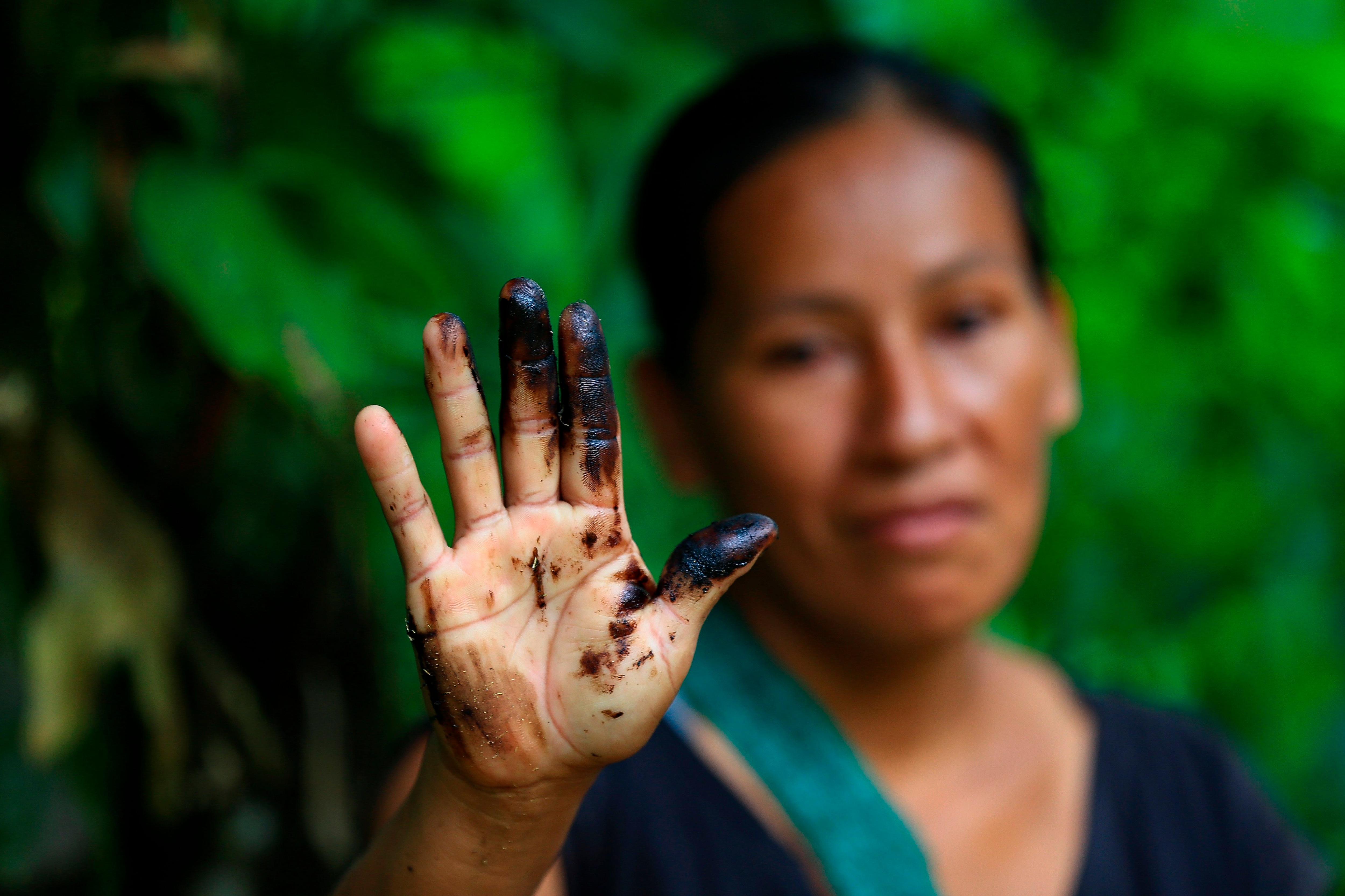 Una indígena de la comunidad de Amarumesa muestra en su mano residuos de petróleo en la Amazonía ecuatoriana (EFE/José Jácome) 