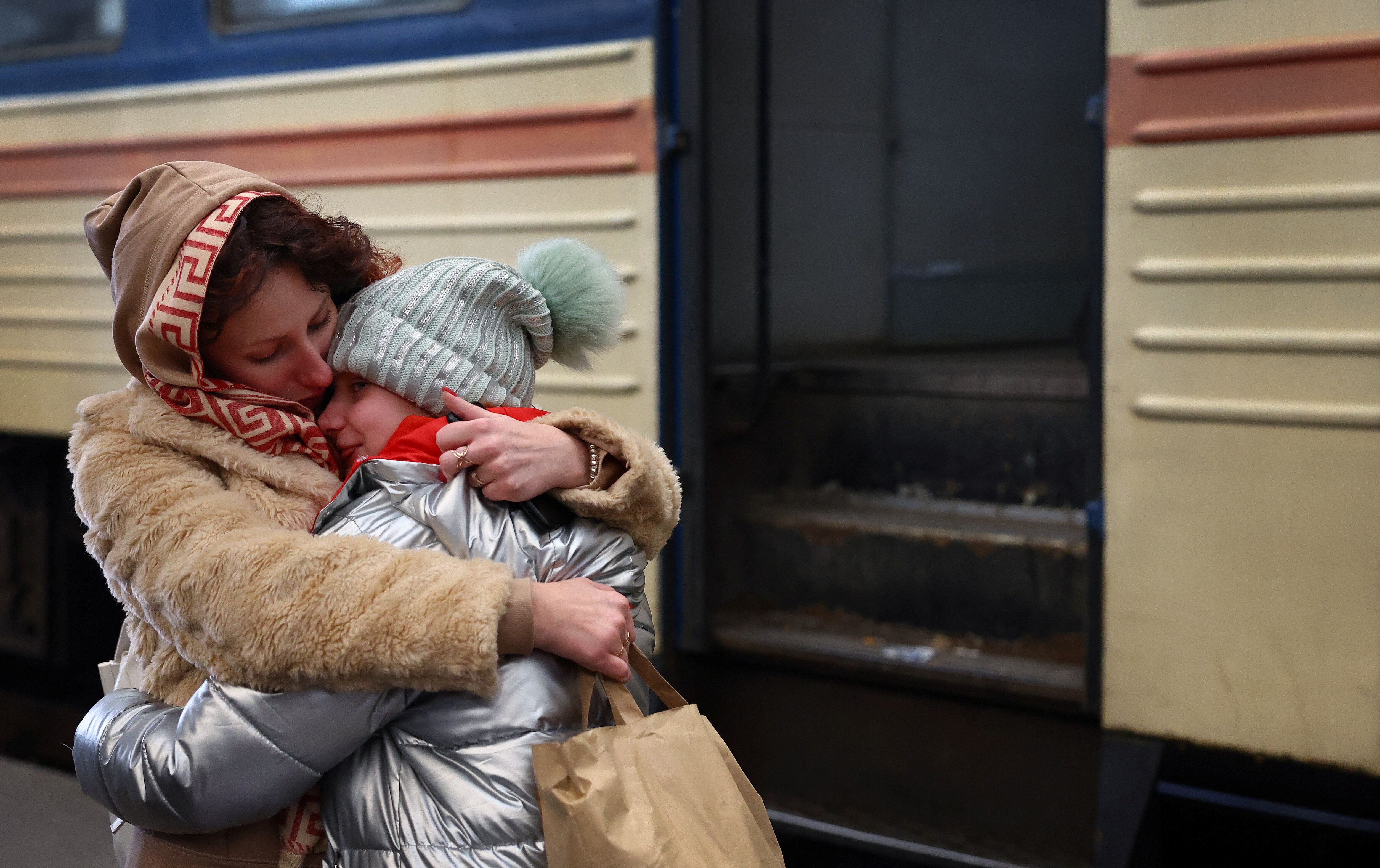 A mother holds her crying daughter after their arrival by train from Kharkiv following Russia?s invasion of Ukraine at the main train station in Lviv, Ukraine, March 4, 2022. REUTERS/Kai Pfaffenbach