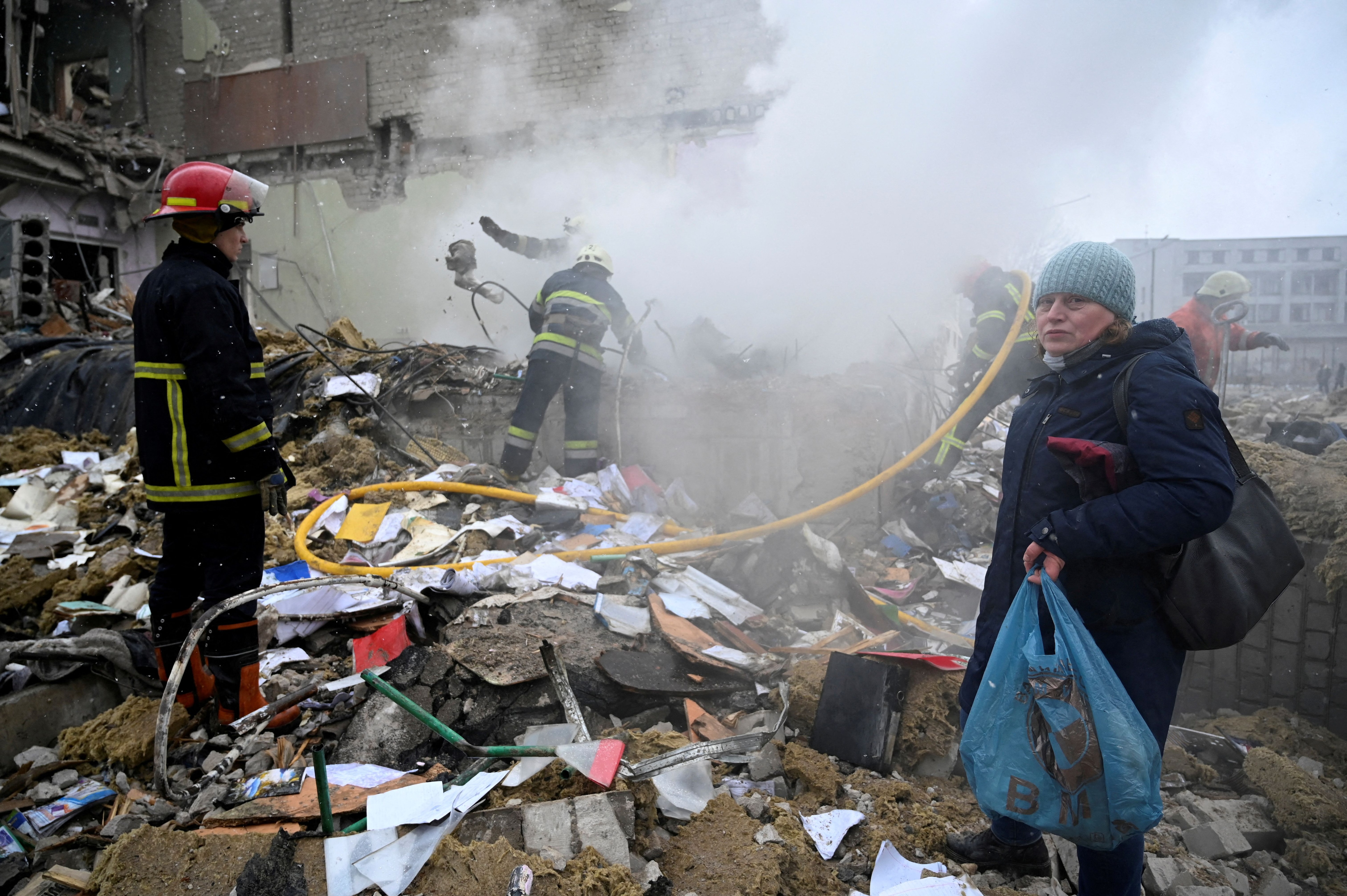Una mujer se encuentra junto a los rescatistas en medio de los escombros de un edificio escolar destruido por los bombardeos, mientras continúa la invasión rusa de Ucrania, en Zhytomyr, Ucrania 4 de marzo de 2022. REUTERS/Viacheslav Ratynskyi