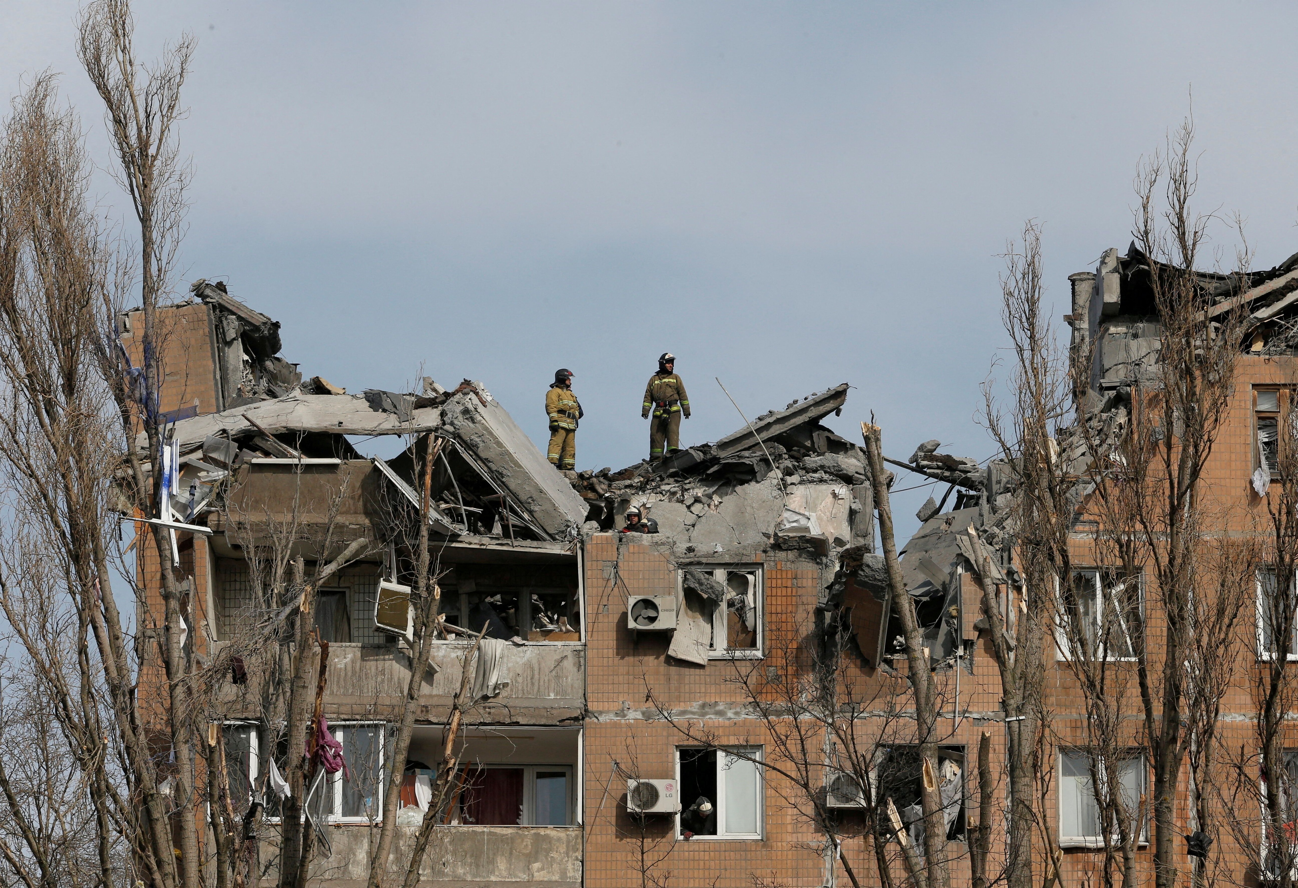 Los bomberos trabajan en un edificio residencial dañado por los bombardeos durante el conflicto entre Ucrania y Rusia en la ciudad de Donetsk, Ucrania, controlada por los separatistas, el 30 de marzo de 2022. (REUTERS/Alexander Ermochenko)