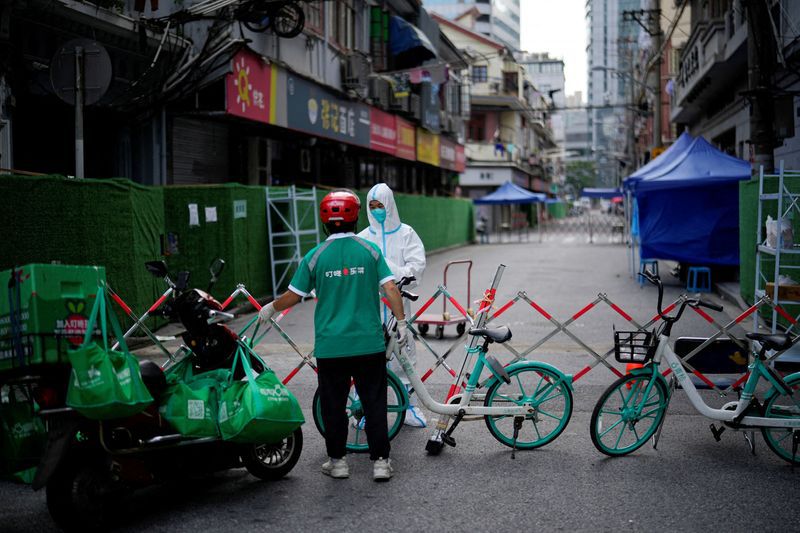 FOTO DE ARCHIVO. Un trabajador con traje de protección recibe comida de un repartidor en una zona residencial cerrada durante el confinamiento, en medio del brote de la enfermedad del coronavirus (COVID-19), en Shanghái, China. 25 de mayo de 2022. REUTERS/Aly Song