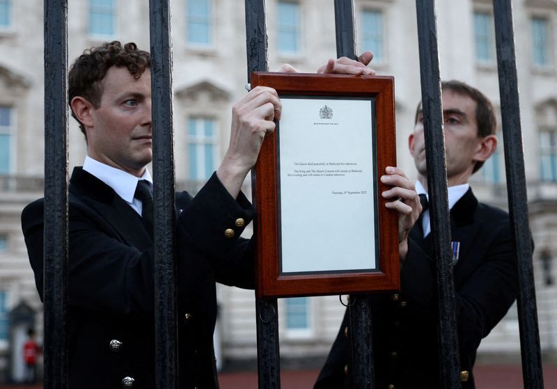 El Personal coloca un cartel anunciando la muerte de la Reina Isabel en una valla fuera del Palacio de Buckingham, después de que la Reina Isabel, la monarca más longeva de Gran Bretaña y la figura de la nación durante siete décadas, murió a los 96 años (REUTERS/Henry Nicholls)