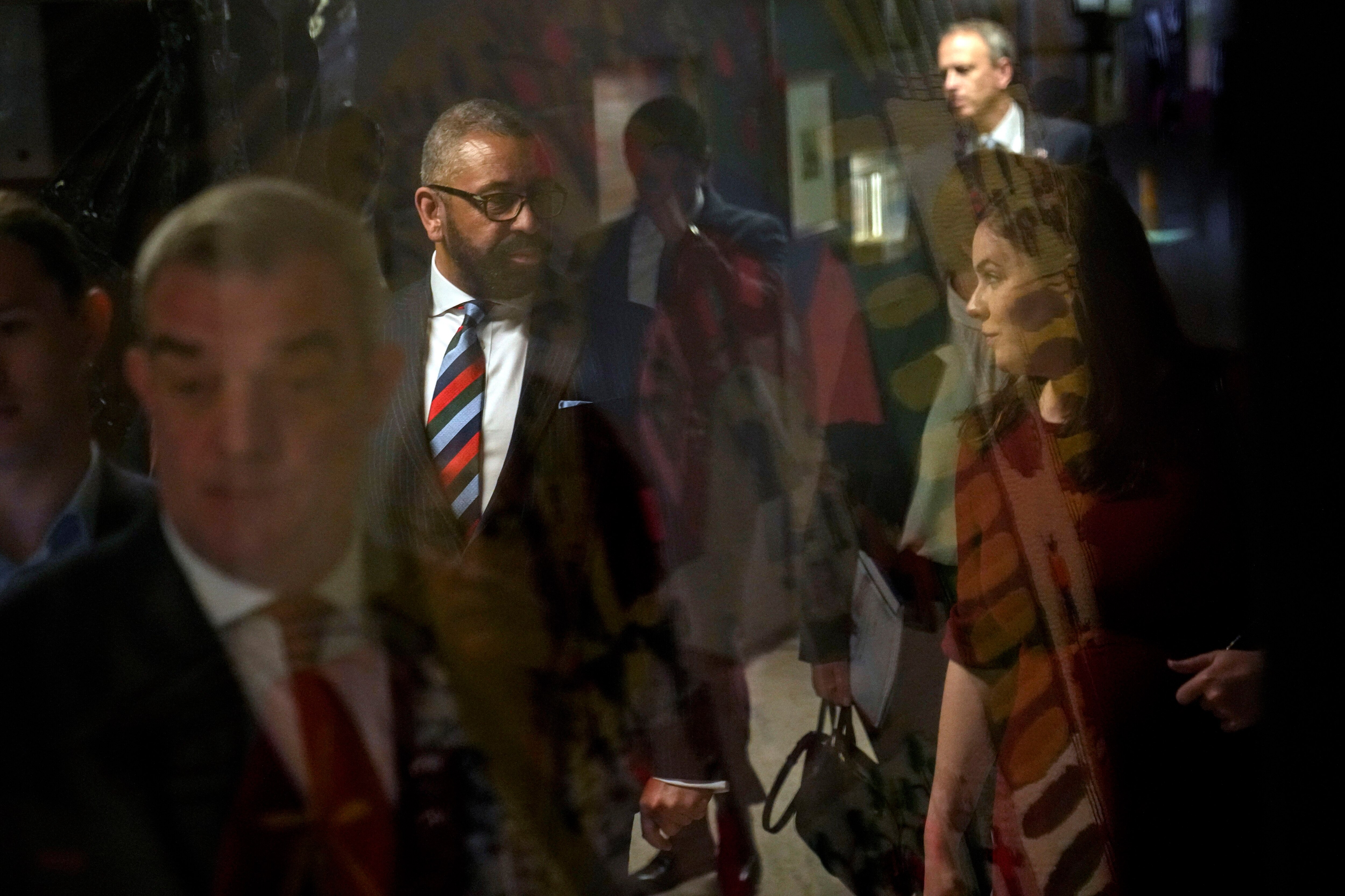 Fotografía tomada a través de una ventana de vidrio en la que se ve al secretario de Estado para Asuntos del Exterior, la Mancomunidad y el Desarrollo de Gran Bretaña, James Cleverly, al centro y la izquierda, a su llegada a una conferencia de prensa en el Centro Cultural Gabriela Mistral en Santiago, Chile, el lunes 22 de mayo de 2023. (AP Photo/Esteban Felix)