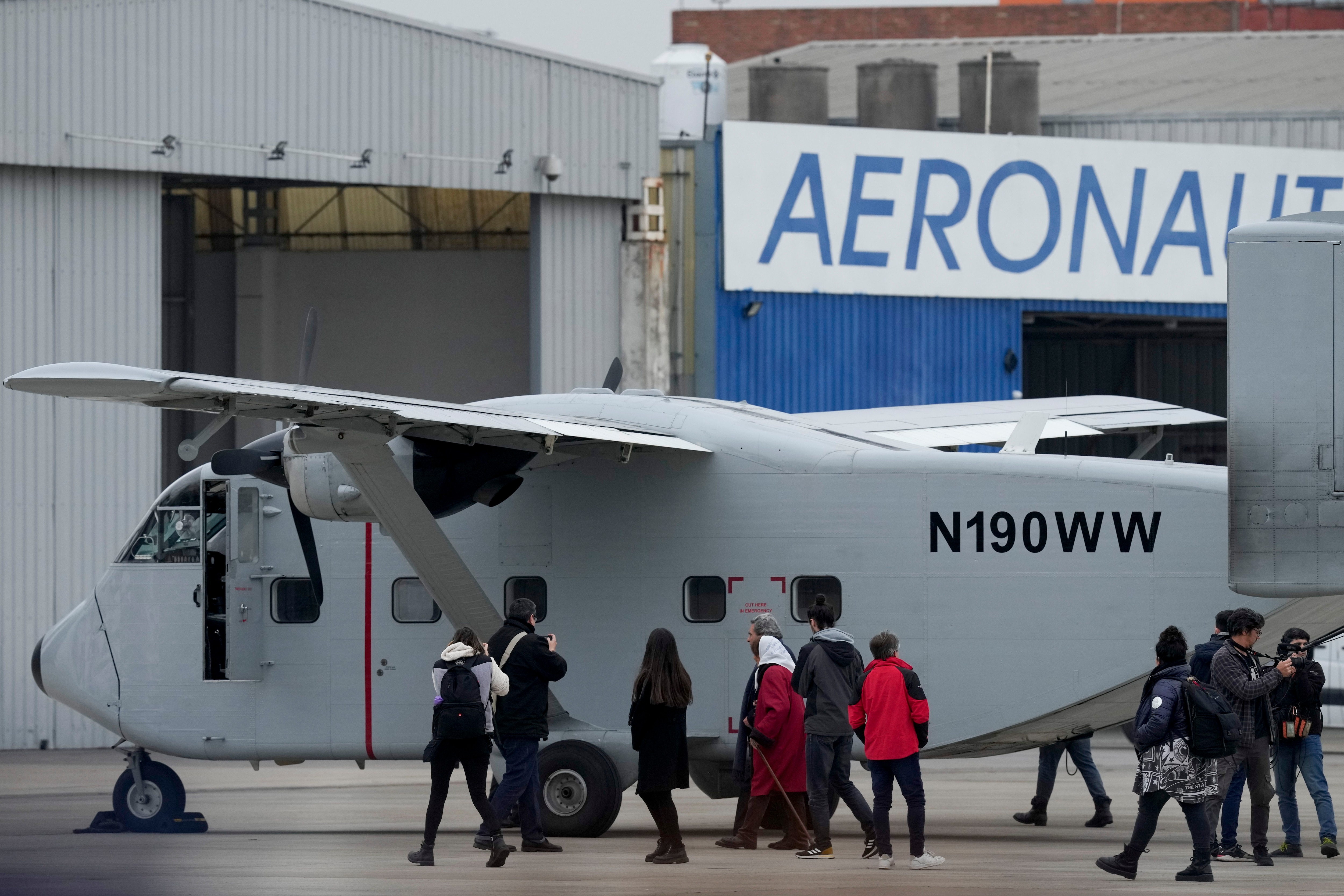 Miembros de organizaciones de derechos humanos caminan frente a la aeronave en Aeroparque. El avión fue uno de los que se utilizaron en los "vuelos de la muerte", en los que detenidos eran arrojados al mar desde las alturas para asesinarlos durante la dictadura militar (AP Foto/Natacha Pisarenko)