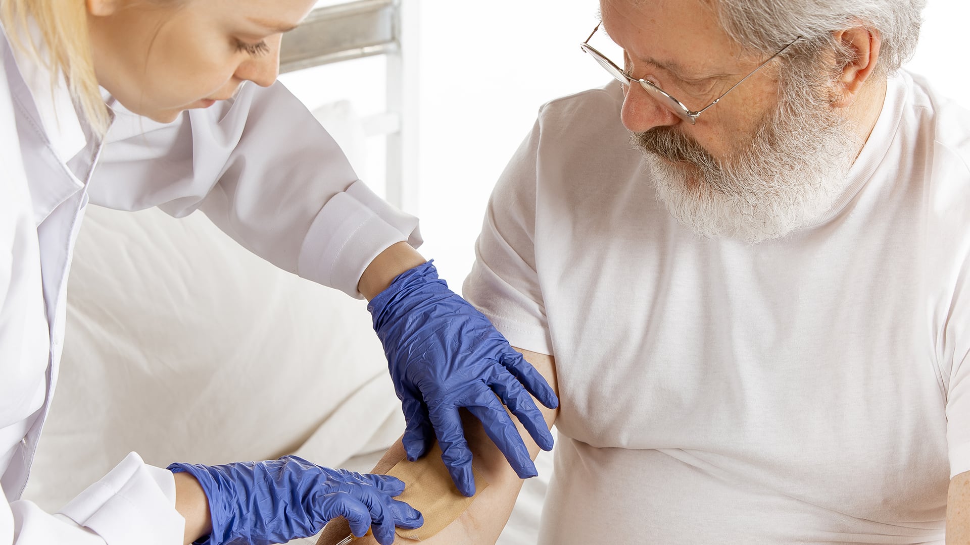 Personal de salud prepara el brazo de un anciano para tomarle una muestra de sangre.